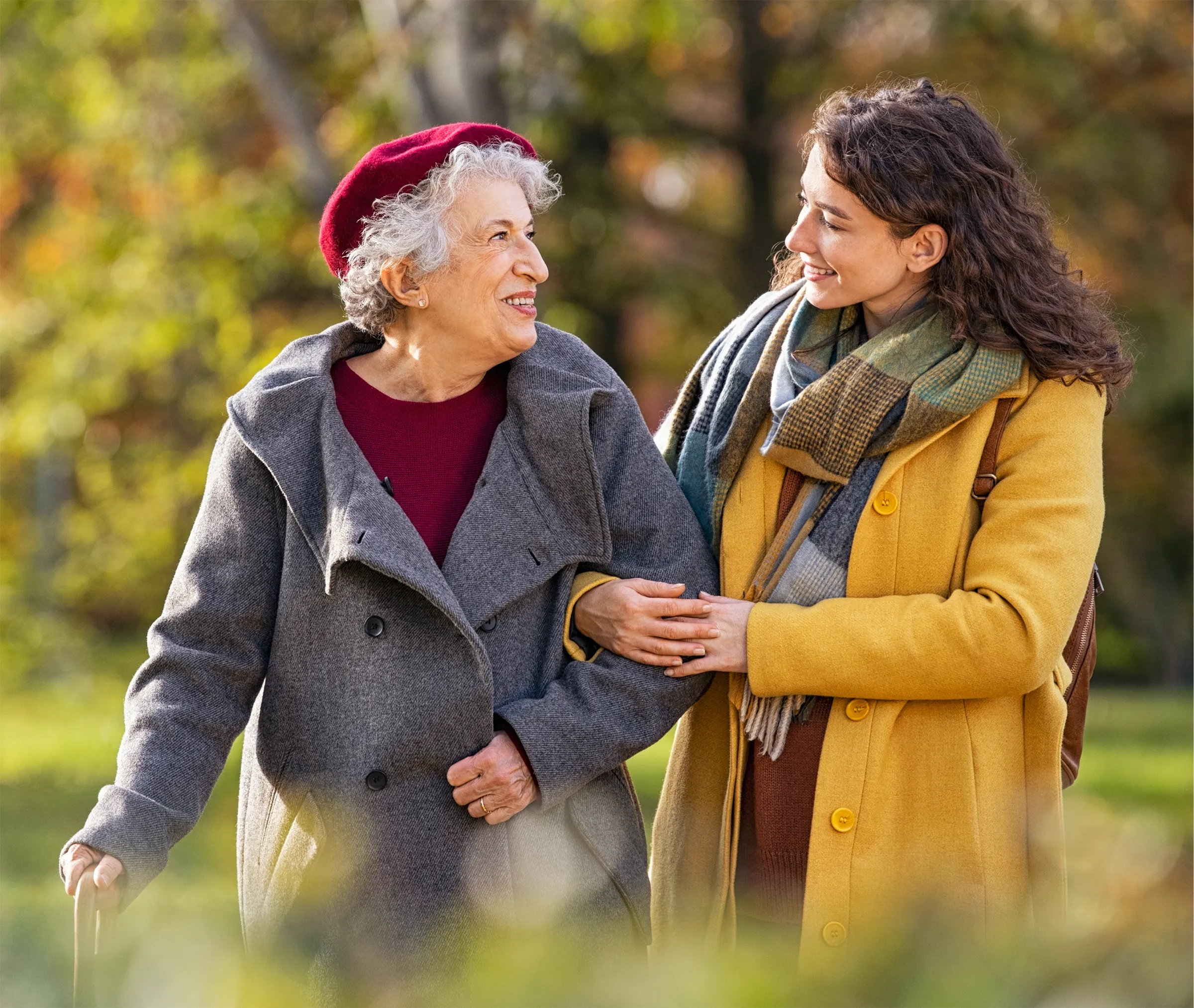 woman helping senior on autumn walk
