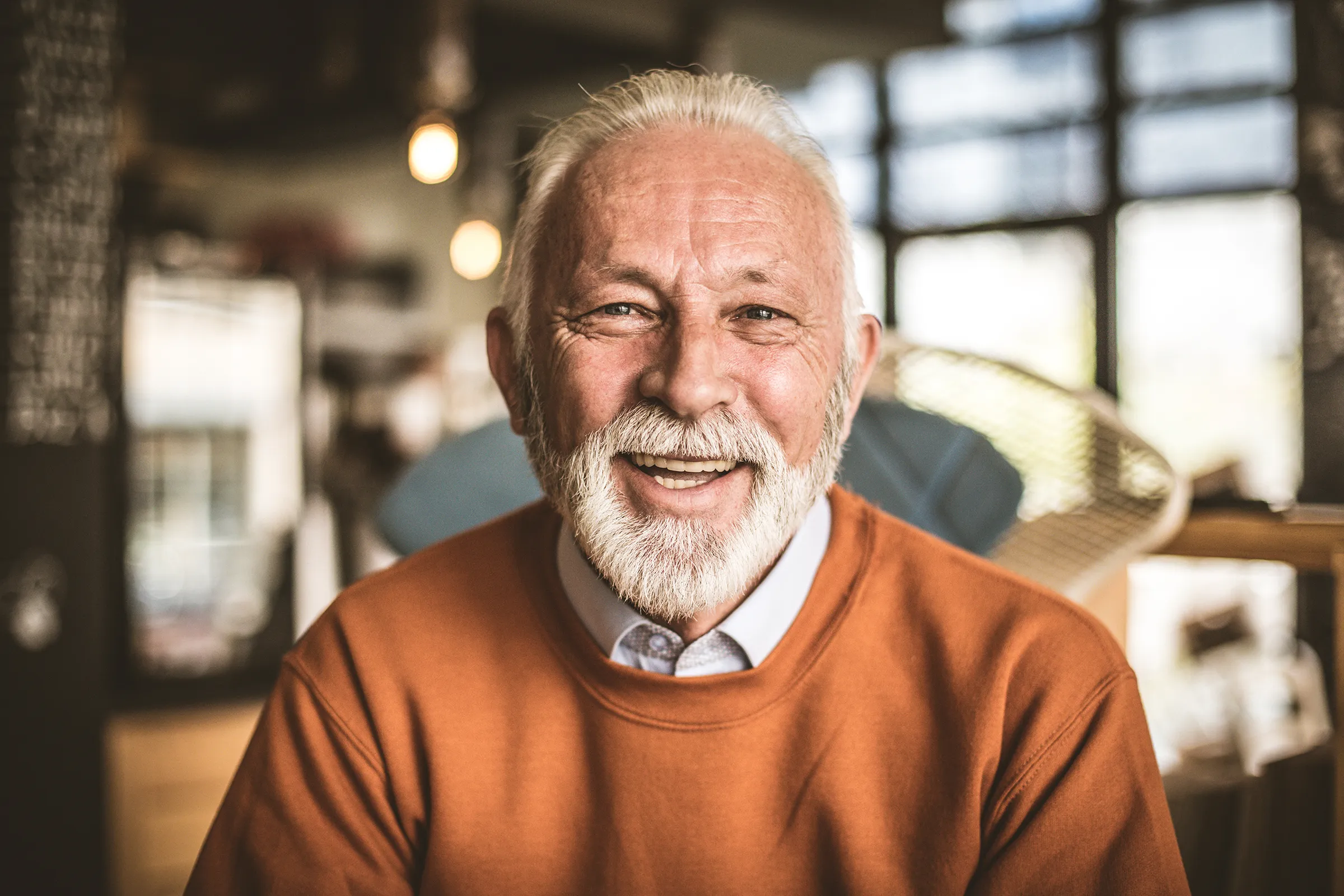 senior man smiling in orange shirt