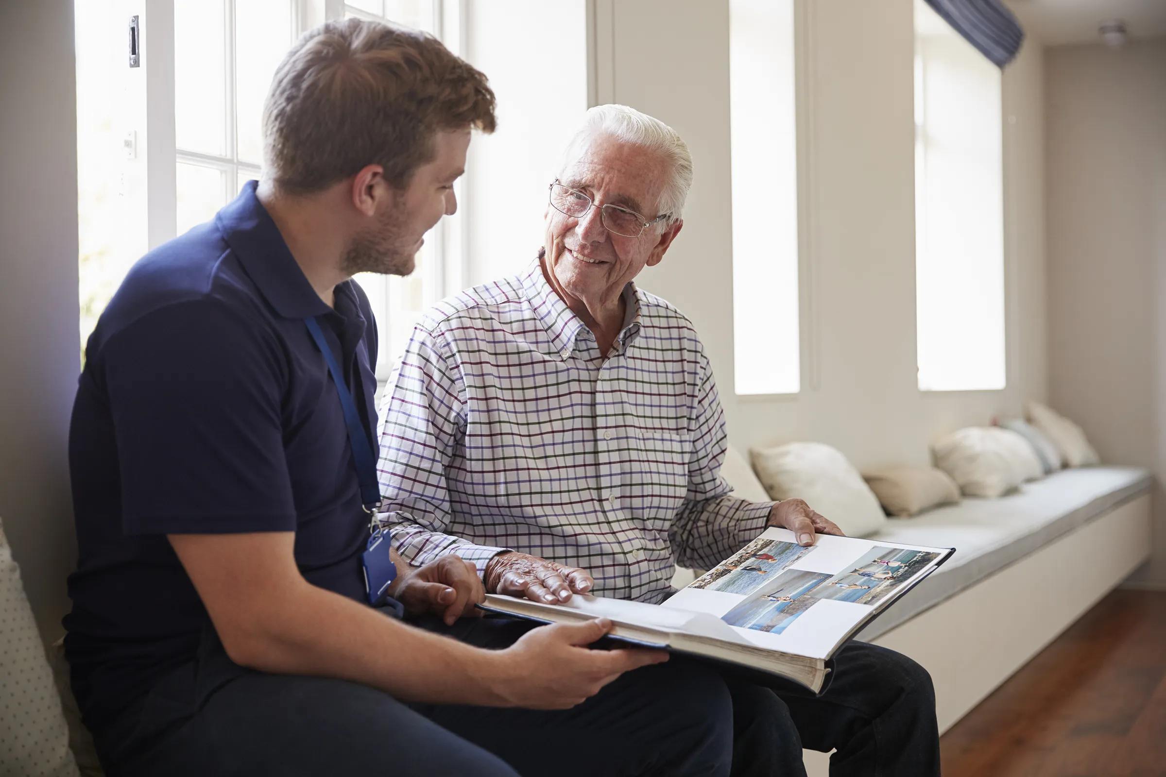 man looking at photo album with memory care provider